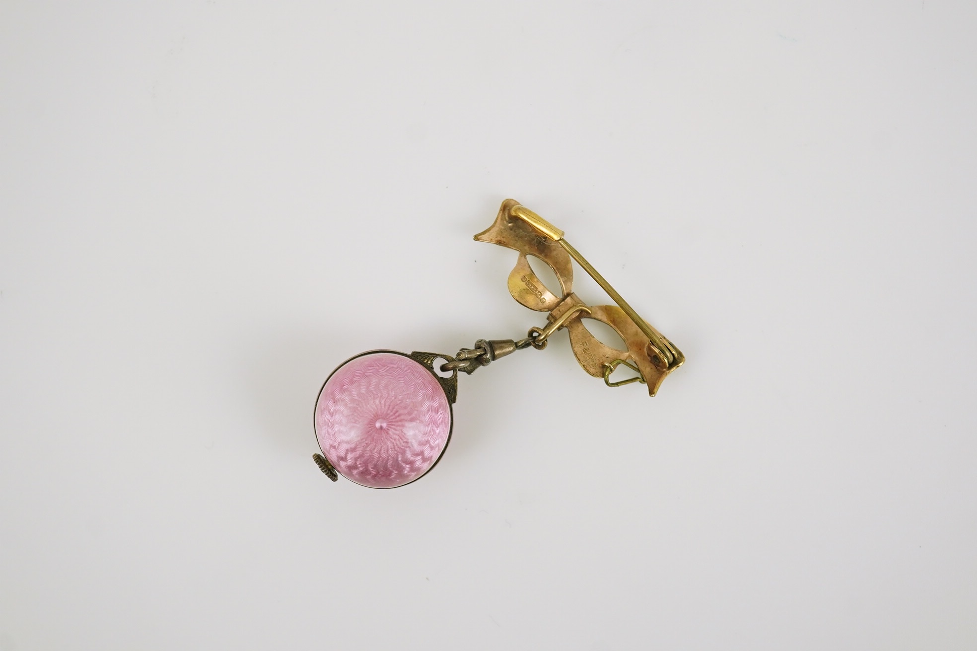 An early to mid 20th century silver and pink guilloche enamel Burger manual wind globe lapel watch, on a later 9ct gold ribbon bow suspension brooch